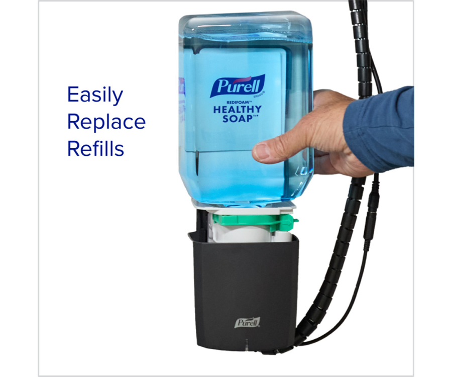 A hand replacing a blue liquid soap refill in a black wall-mounted dispenser with visible tubing. PURELL® CX10™ Chrome Counter Mount Soap Dispenser (12.5 in. x 10.375 in. x 5.25 in., 1/Case)